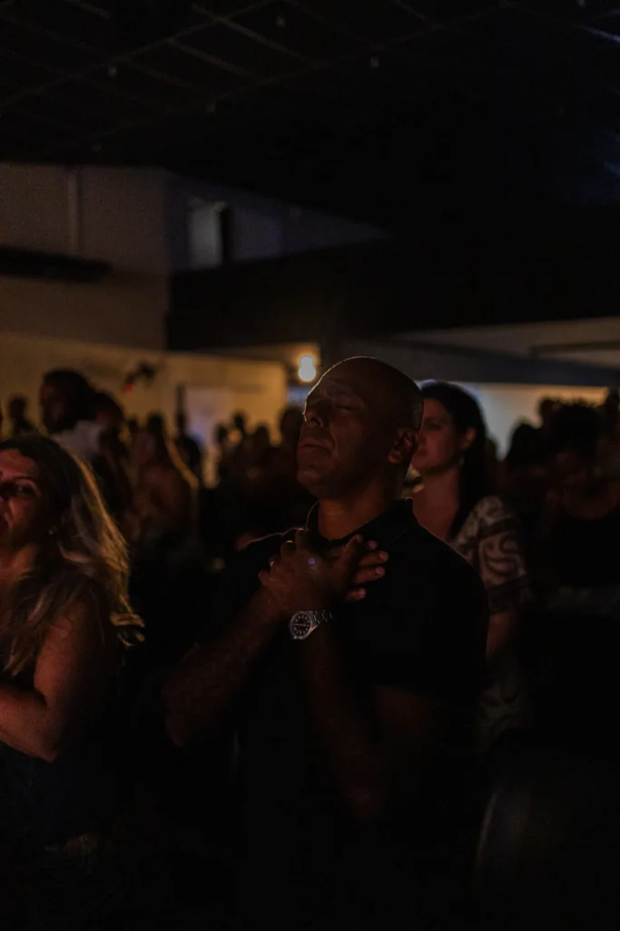 Participante ajoelhado, com as mãos apoiadas no chão, recebe apoio de outra pessoa.