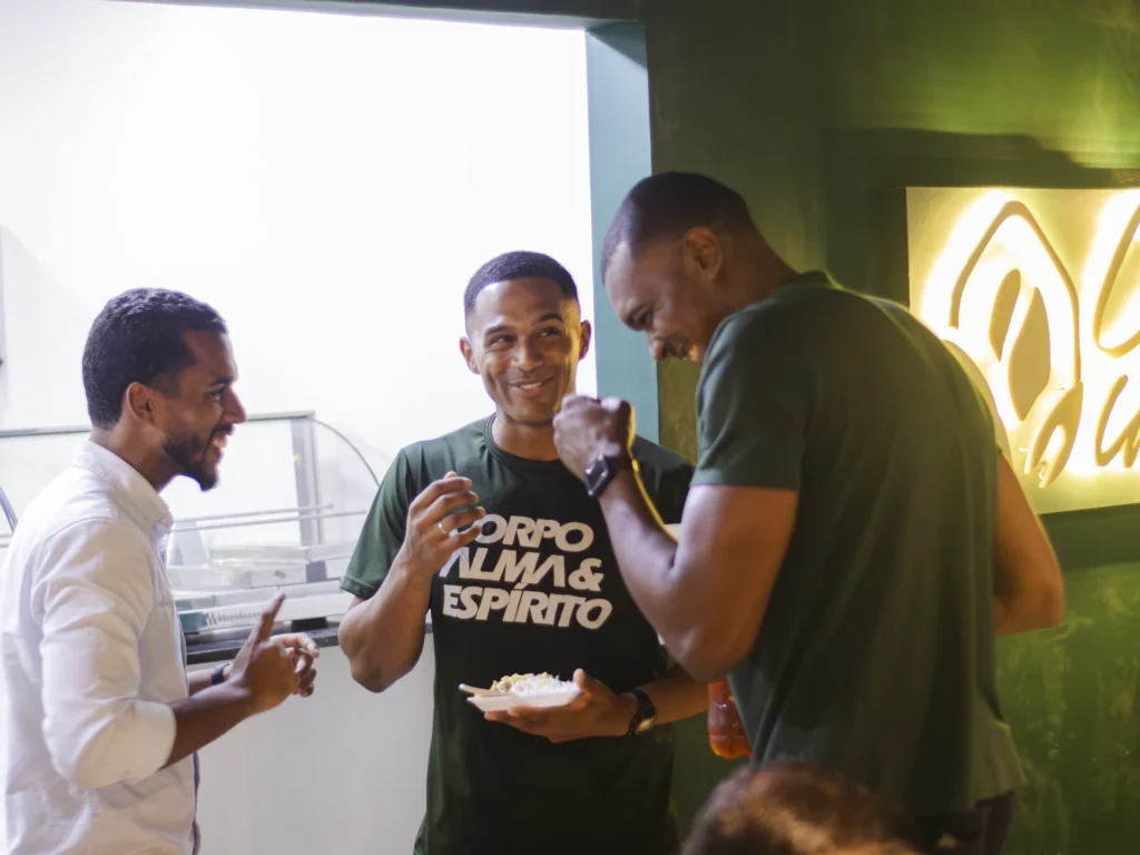 Três participantes conversam em torno de uma mesa durante uma atividade.