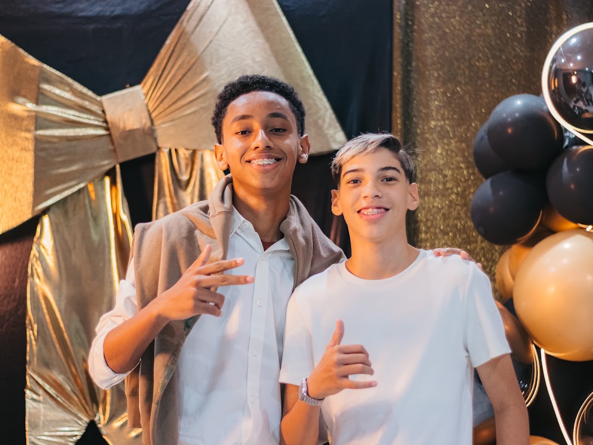 Dois adolescentes juntos diante da decoração dourada da Noite do Oscar.